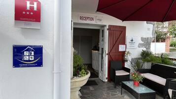 A hotel reception area with a sign indicating it is a 2020-classified hotel. There is a reception desk, a sign for the hotel named "Ursula L Hotel," and a sign for "Tourisme & Handicap."
