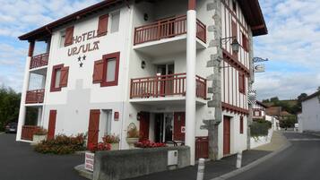 A two-story hotel with a balcony on the second floor, a reception area, and a sign indicating parking availability.