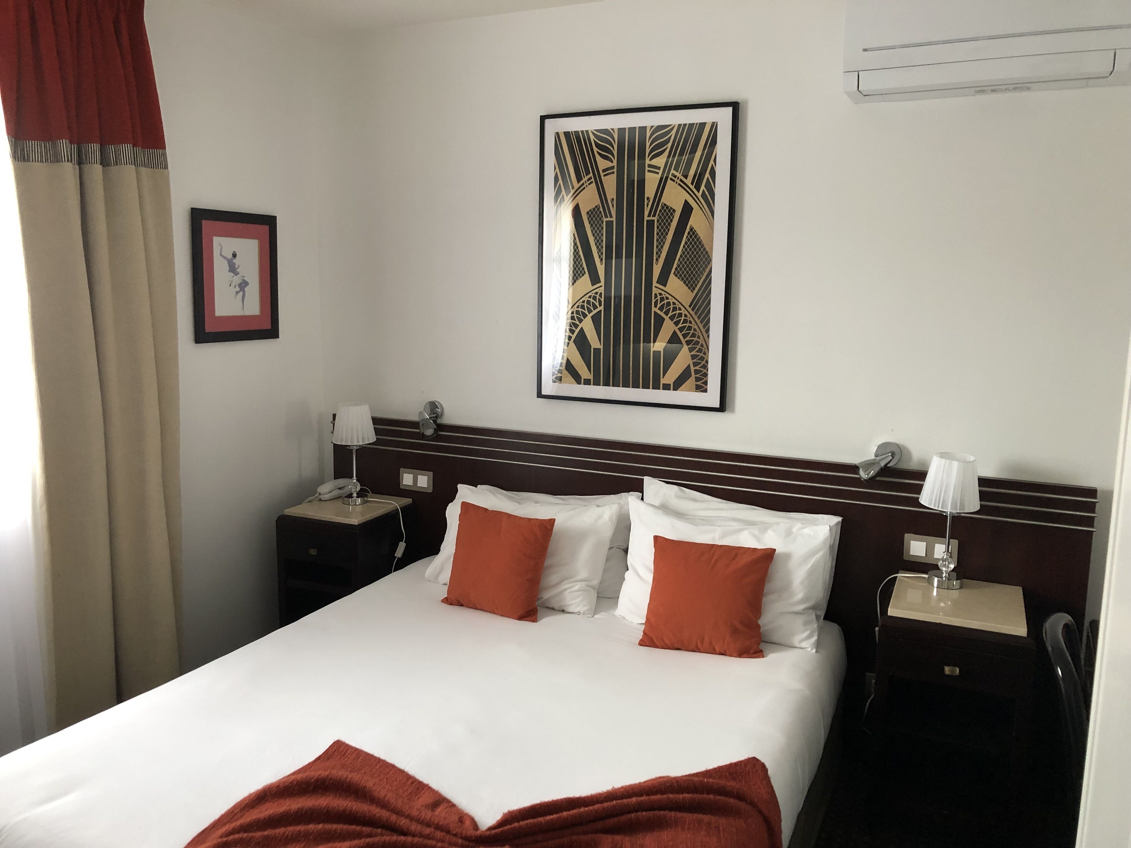 Habitación de hotel con una cama grande, dos mesitas de noche, una lámpara de pared y un cuadro enmarcado.