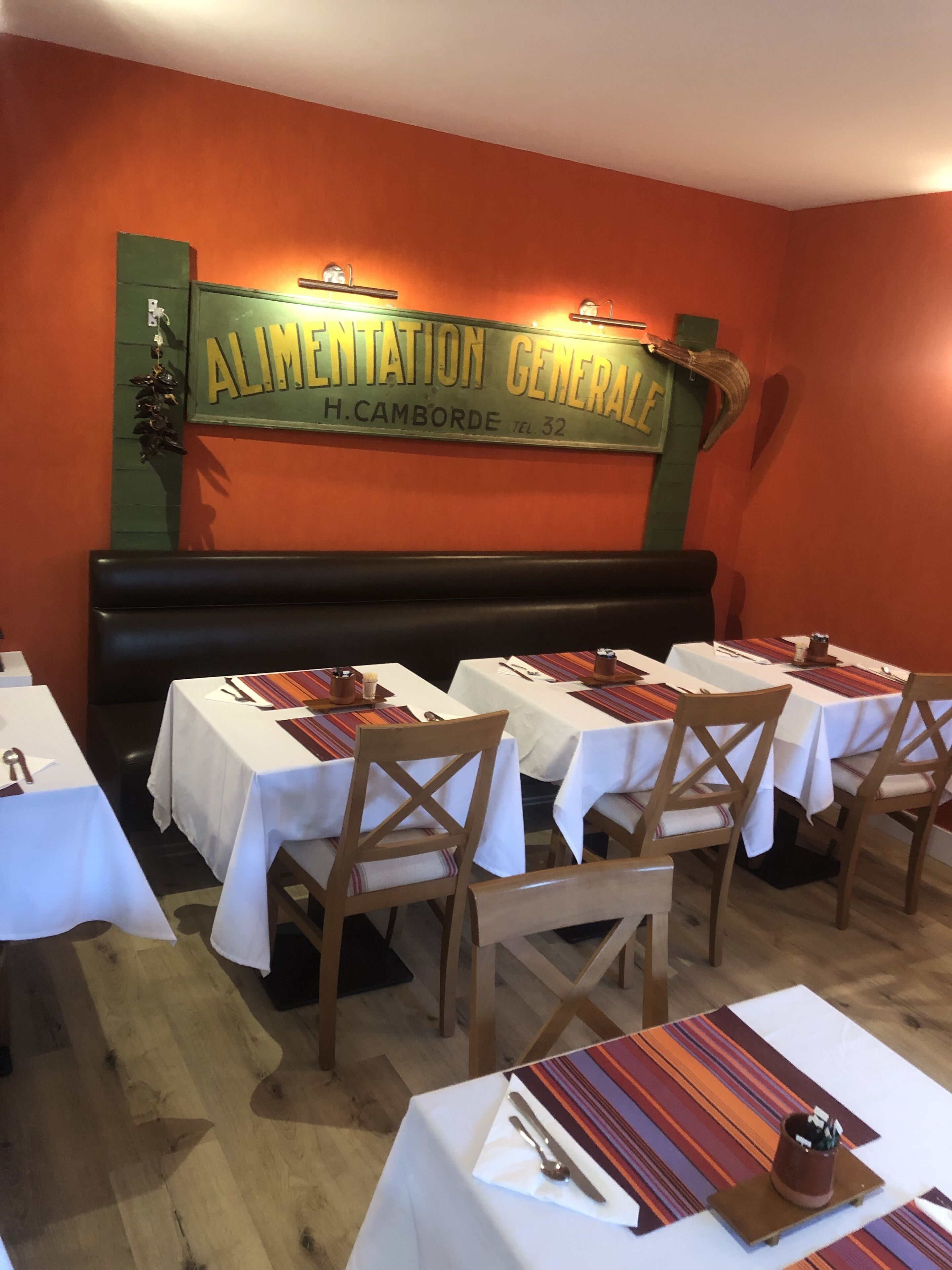 A restaurant interior with tables set for dining, a sign above the tables, and a wooden bench.