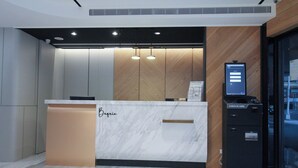 A reception desk with a marble top, a wooden accent wall, and a digital display. - Hotel B (Taipei)