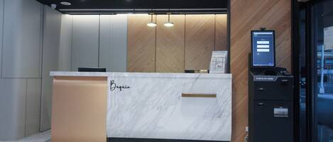 A reception desk with a marble top, a wooden accent wall, and a digital display.
