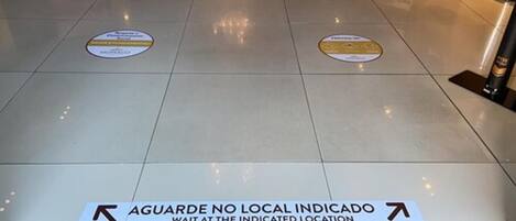 Un suelo con señales de orientación e indicación para esperar en el lugar señalado.