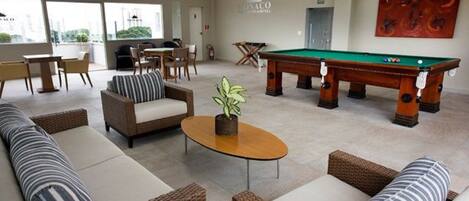 A lounge area with sofas, a pool table, and a dining table.