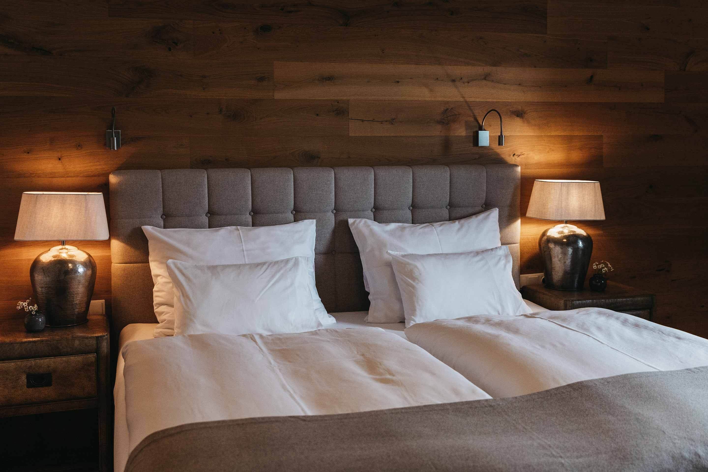 A neatly made bed with white linens, a tufted headboard, and two bedside lamps on wooden nightstands.