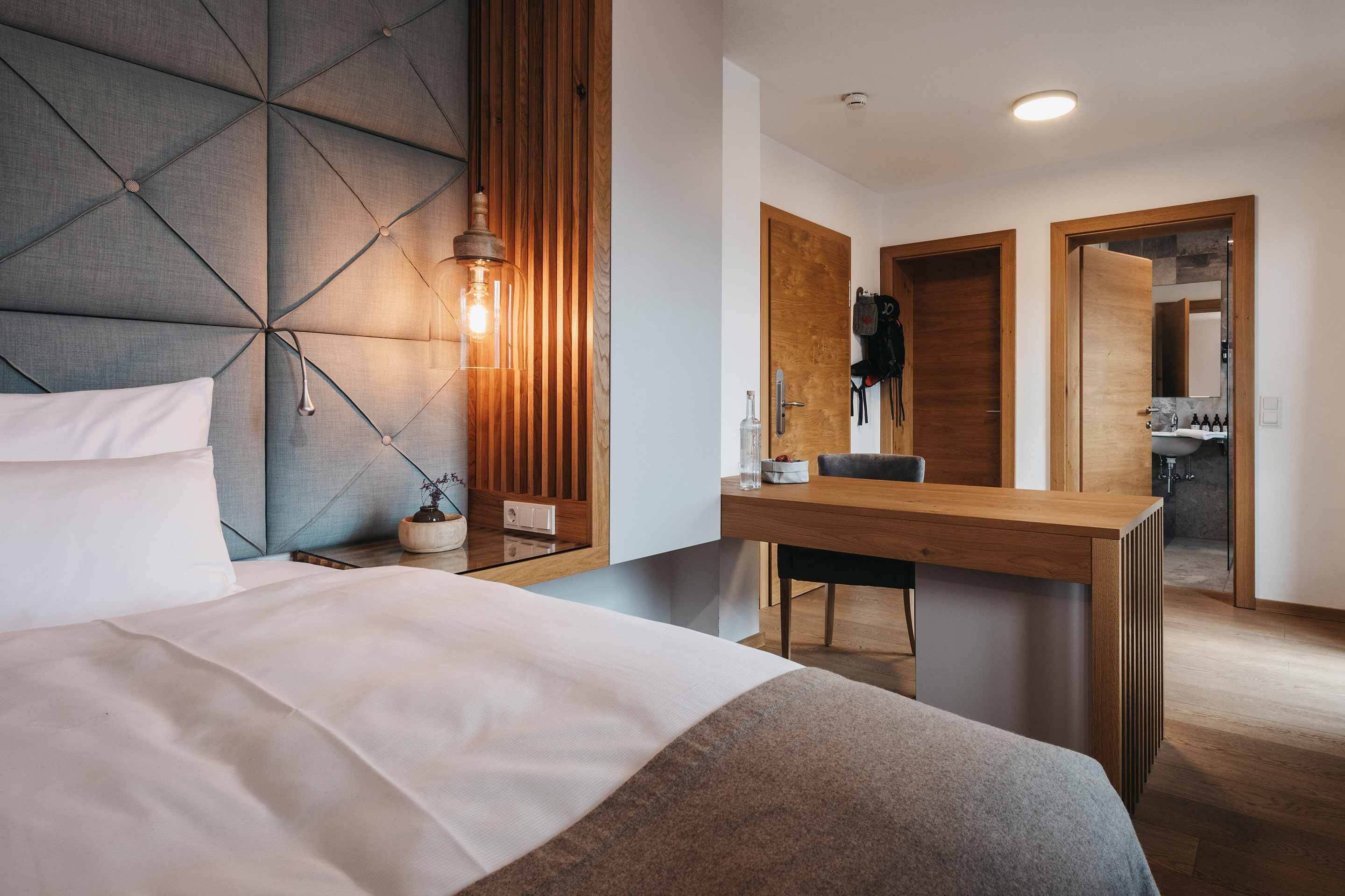 Ein modernes Hotelzimmer mit einem großen Bett, einem Holztisch und einem Spiegel.