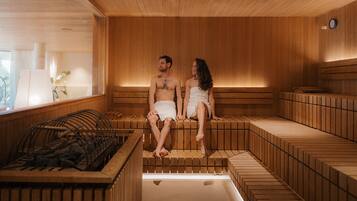 Una sauna con bancos de madera y suelo calefaccionado, una ventana con vistas y un reloj en la pared.