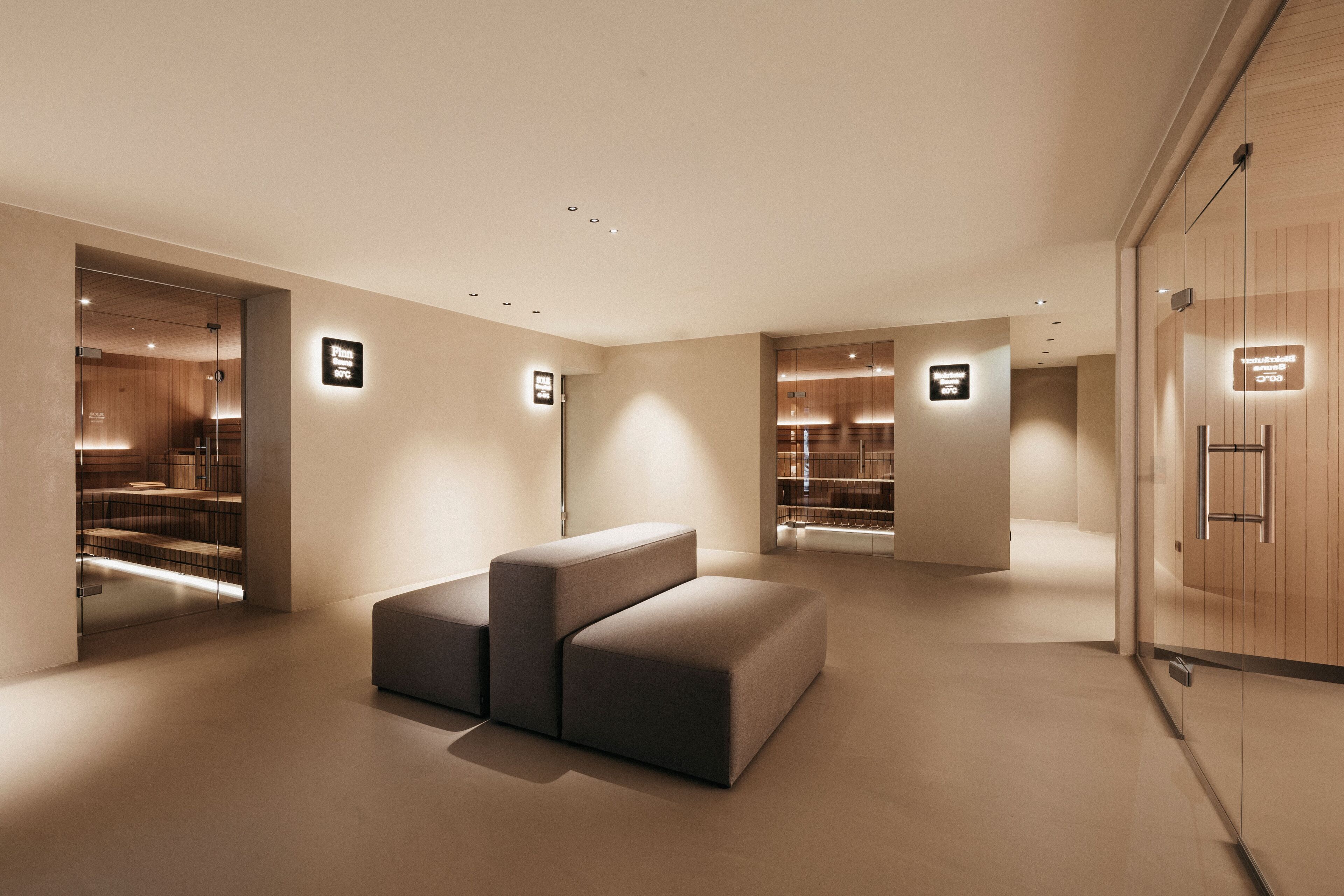 A modern interior with a sectional sofa, recessed lighting, and wooden panel walls.