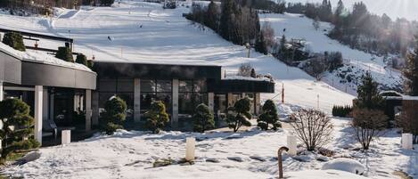A modern building with a ski slope in the background.