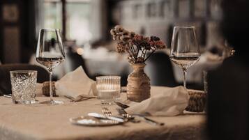 A table set for dining with wine glasses, a vase with flowers, and a candle.