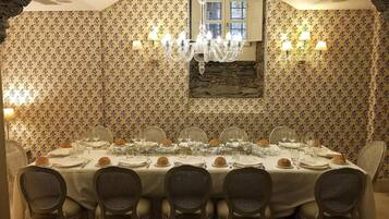 A dining room with a round table set for six, surrounded by wicker chairs.