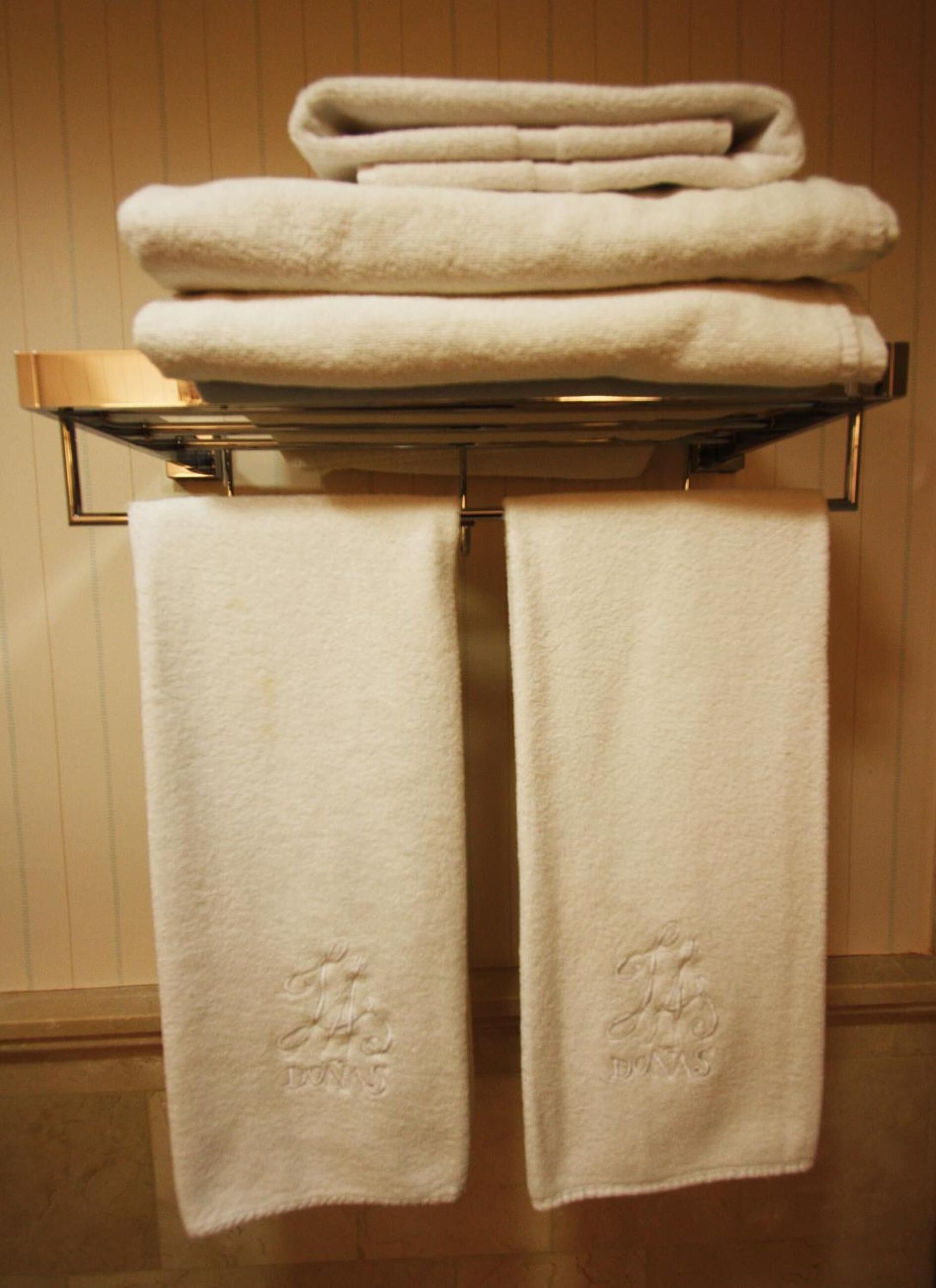 A stack of white towels on a metal towel rack with two towels hanging below.