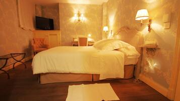 Una habitación de hotel con una cama, televisión, una silla y un escritorio con lámpara.