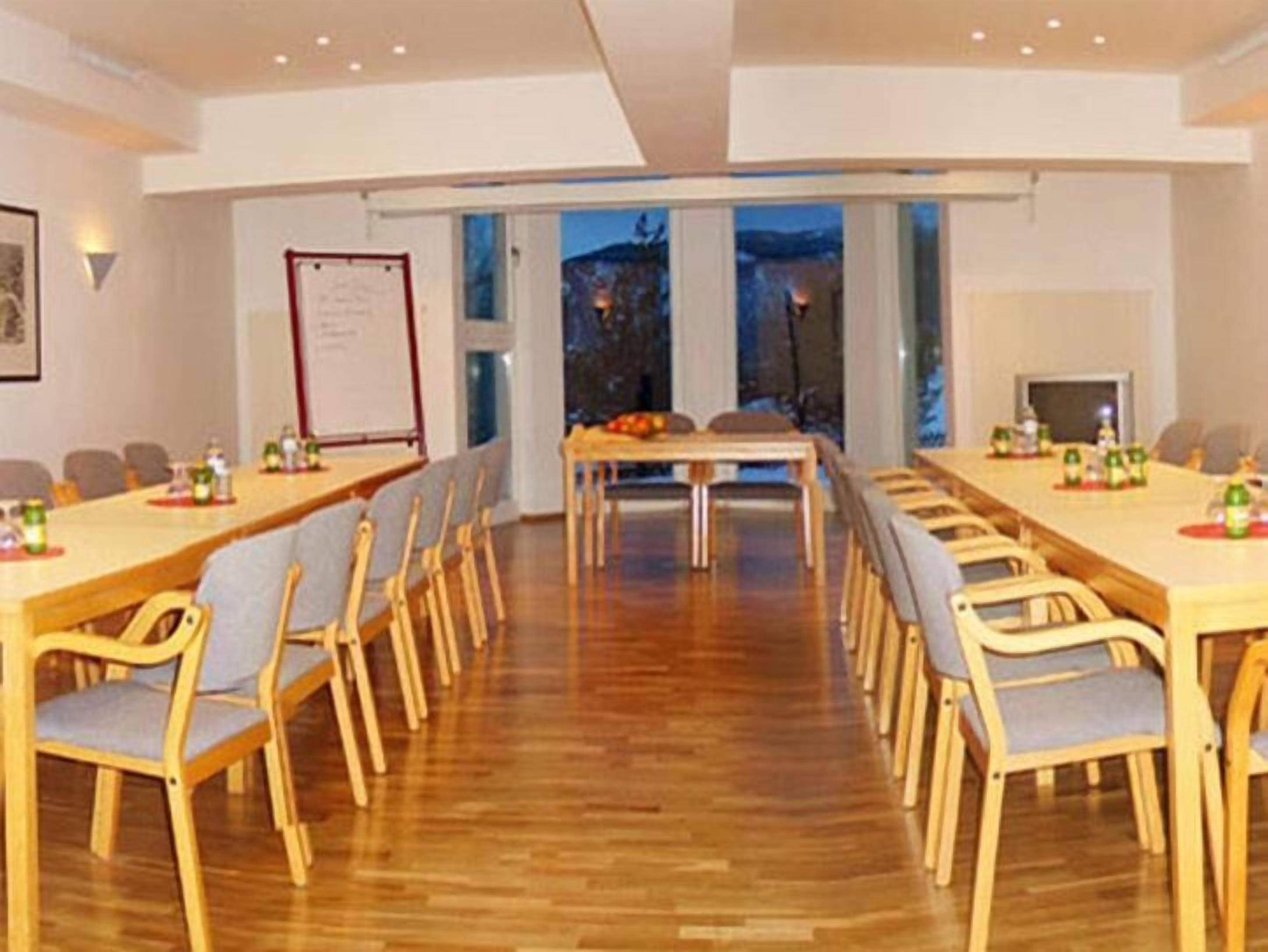 A conference room with wooden tables and chairs, a whiteboard, and a large window with a view of the outdoors.