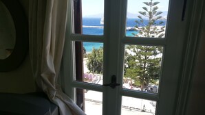 Una ventana con vista al mar, un árbol y un edificio.