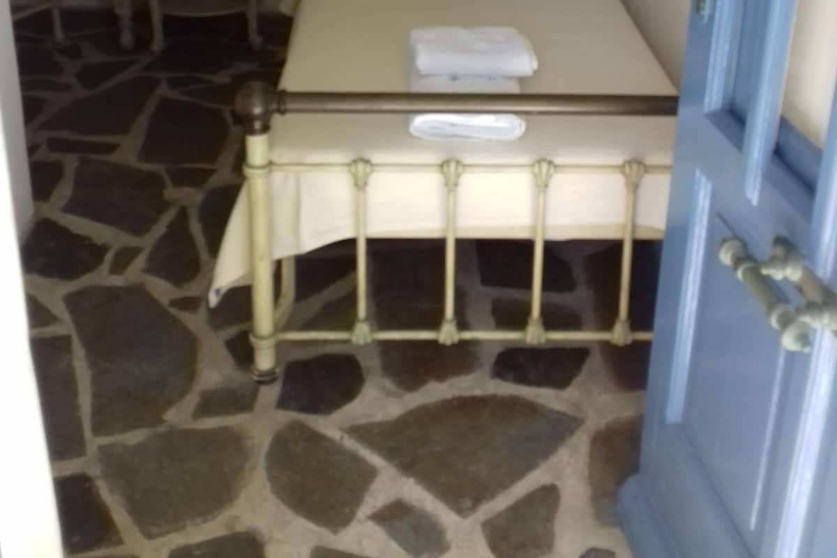 A bedroom with a bed, a bedside table, a lamp, and a door.