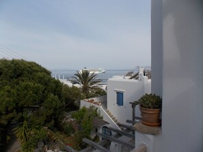 A coastal building with a staircase leading to a balcony overlooking the sea. - Studios and Suites Rania (Mykonos)