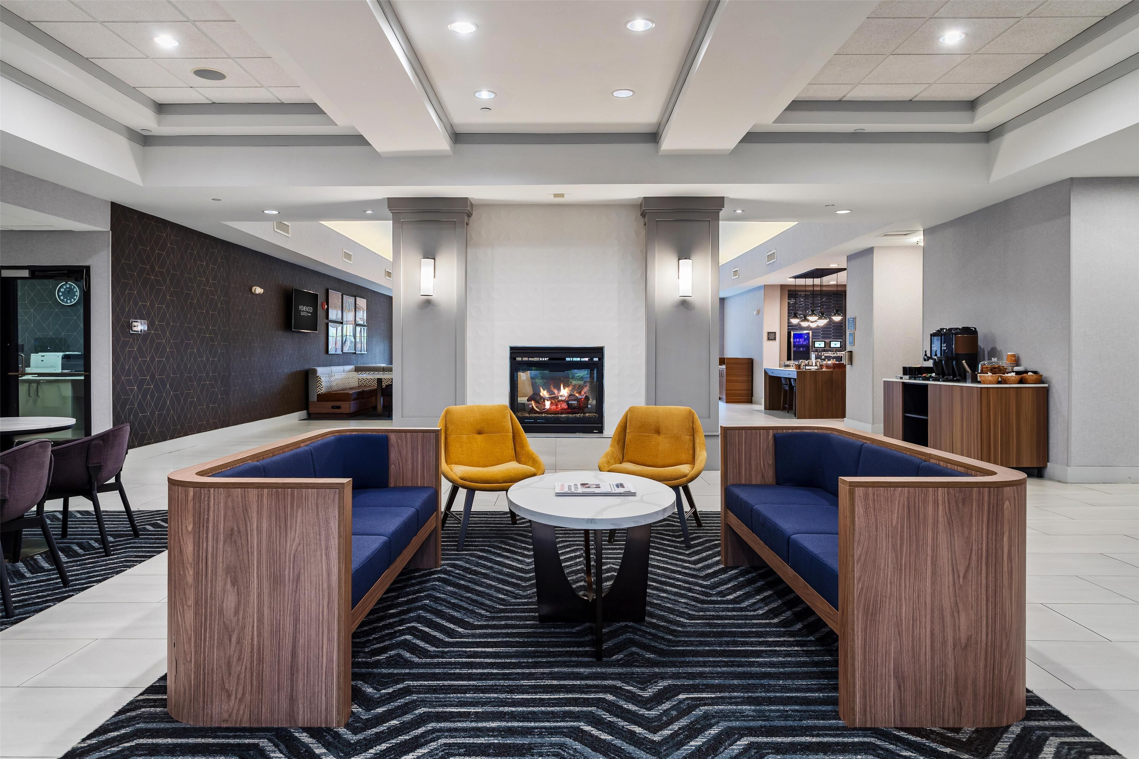 A modern lobby with a fireplace, seating area, and a bar.