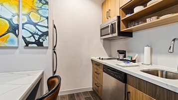 Una cocina moderna con microondas, lavavajillas y armarios de madera. Hay dos cuadros abstractos en la pared.