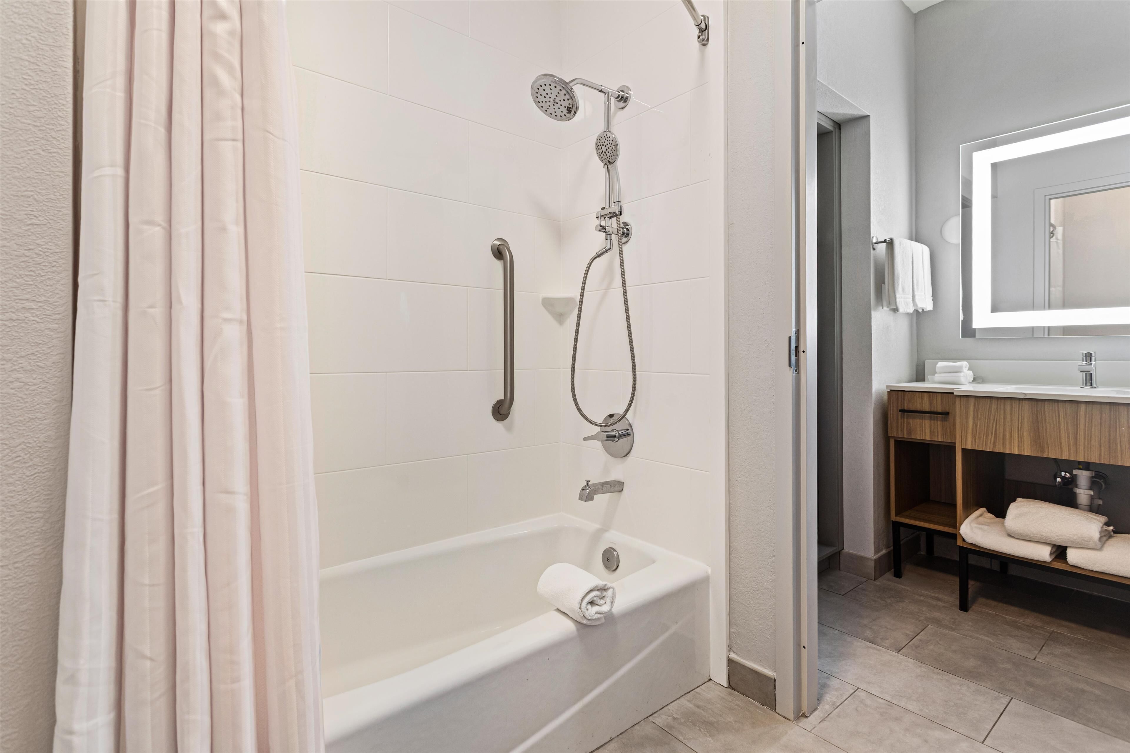A modern bathroom with a bathtub, shower, and vanity.