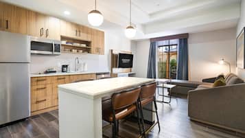 A modern kitchen with wooden cabinets, a stainless steel refrigerator, and a central island with bar stools.