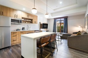 Une cuisine moderne avec des meubles en bois, un réfrigérateur en acier inoxydable et un îlot central doté de tabourets de bar.