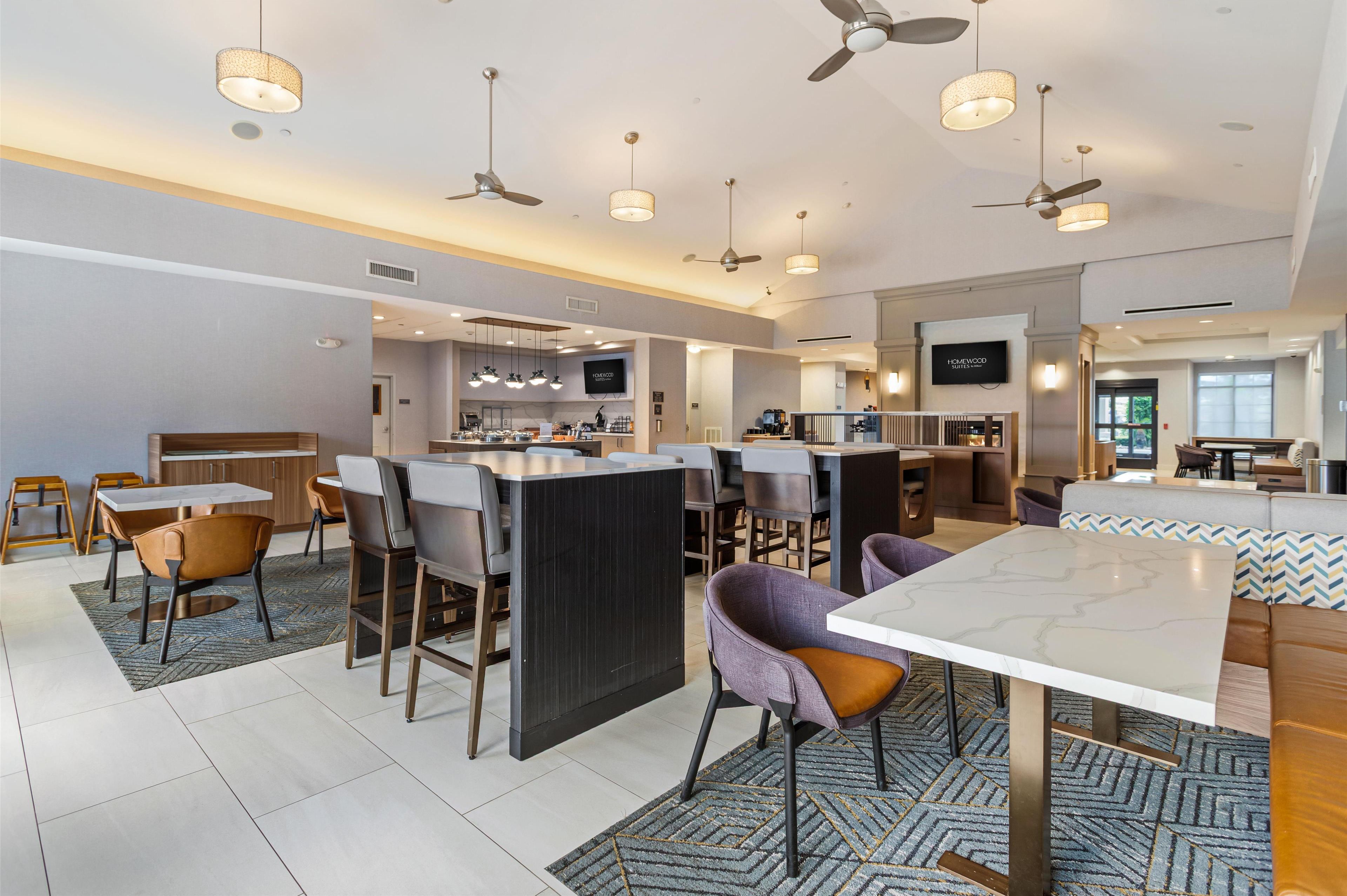 A modern hotel lobby with a bar area, seating, and a television screen.