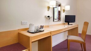 A hotel room with a wooden desk, a chair, a flat-screen TV, a hairdryer, and a coffee maker. - Days Inn by Wyndham Southampton Rownhams (Southampton)