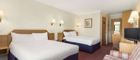 A hotel room with two beds, a TV, and a sofa.