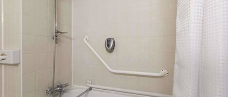 A bathroom with a bathtub, a shower, and a handrail.