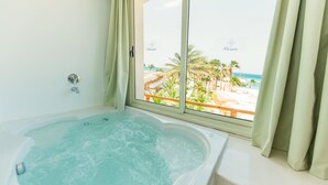 A bathroom with a large bathtub and a window overlooking a beach. - Meraki Resort - Adults Only - All inclusive (Hurghada)