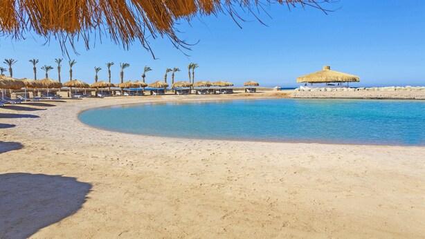 A beach with thatched umbrellas and palm trees, a clear blue sky, and a calm sea. - Meraki Resort - Adults Only - All inclusive (Hurghada)