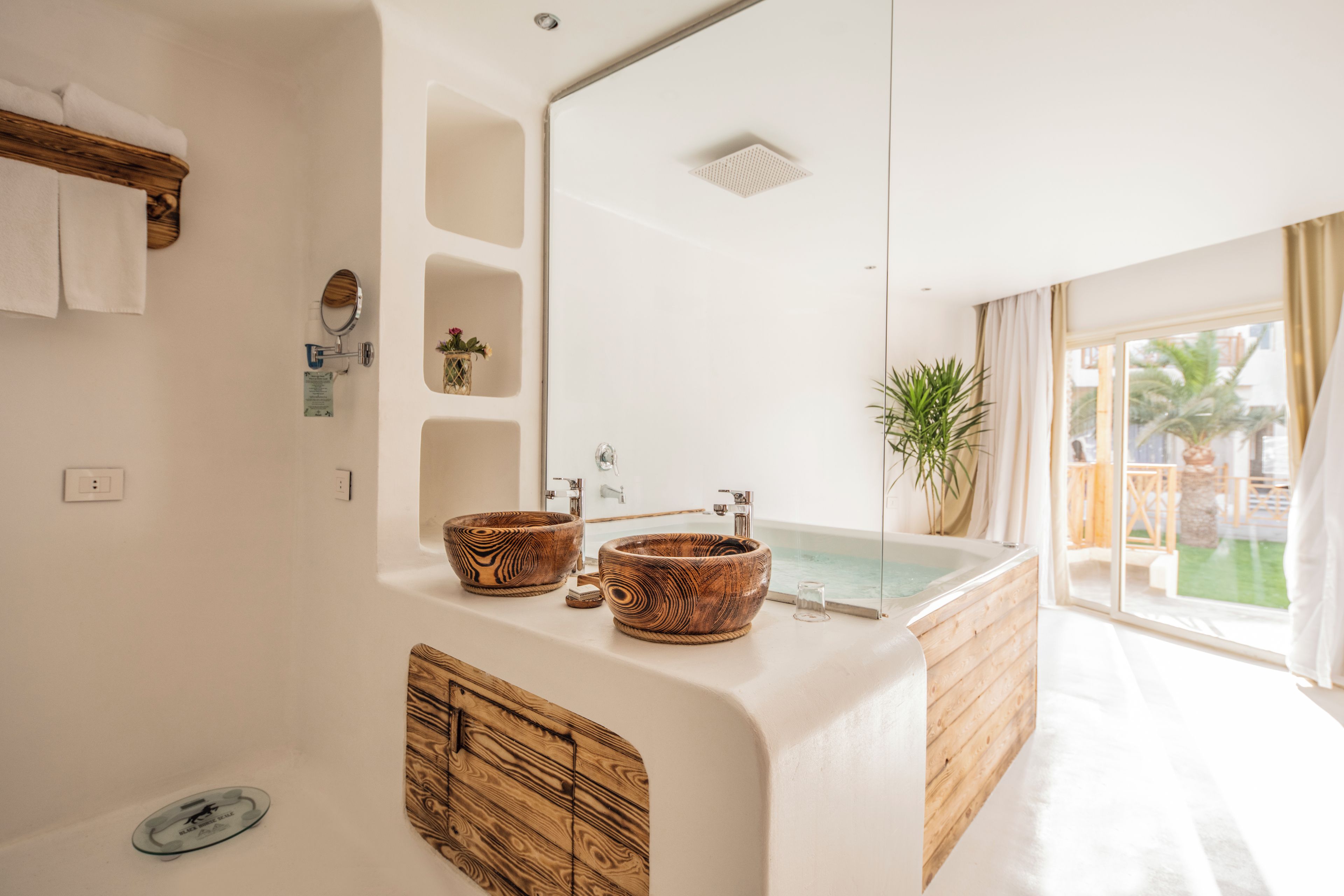 Une salle de bain moderne avec un grand meuble-lavabo en bois, deux bols en bois, un lavabo en verre et une baignoire.