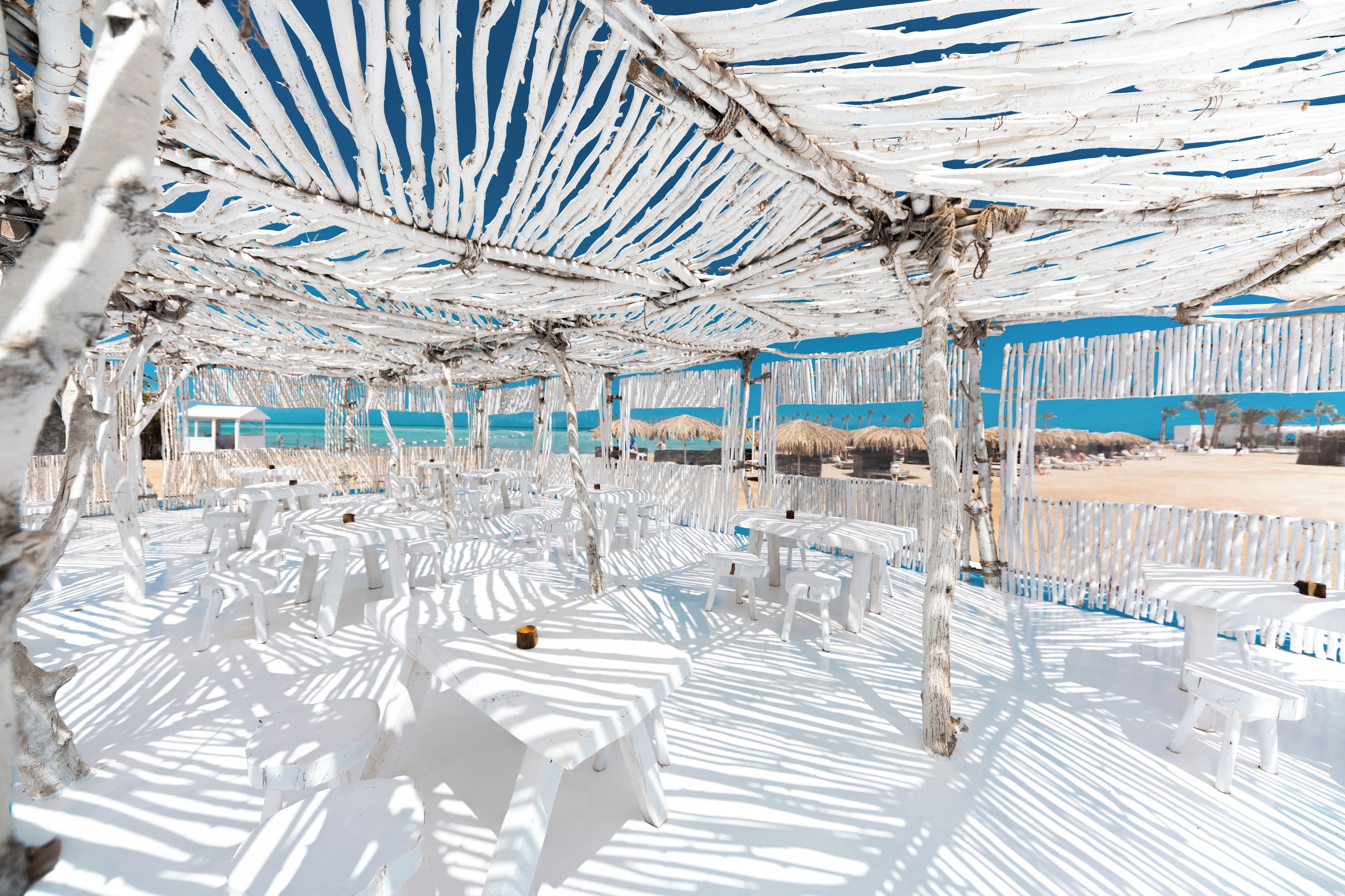 A beachside area with white plastic furniture and a white canopy structure.