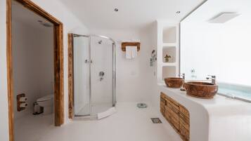 A modern bathroom with a glass shower, wooden accents, and a view of the ocean.