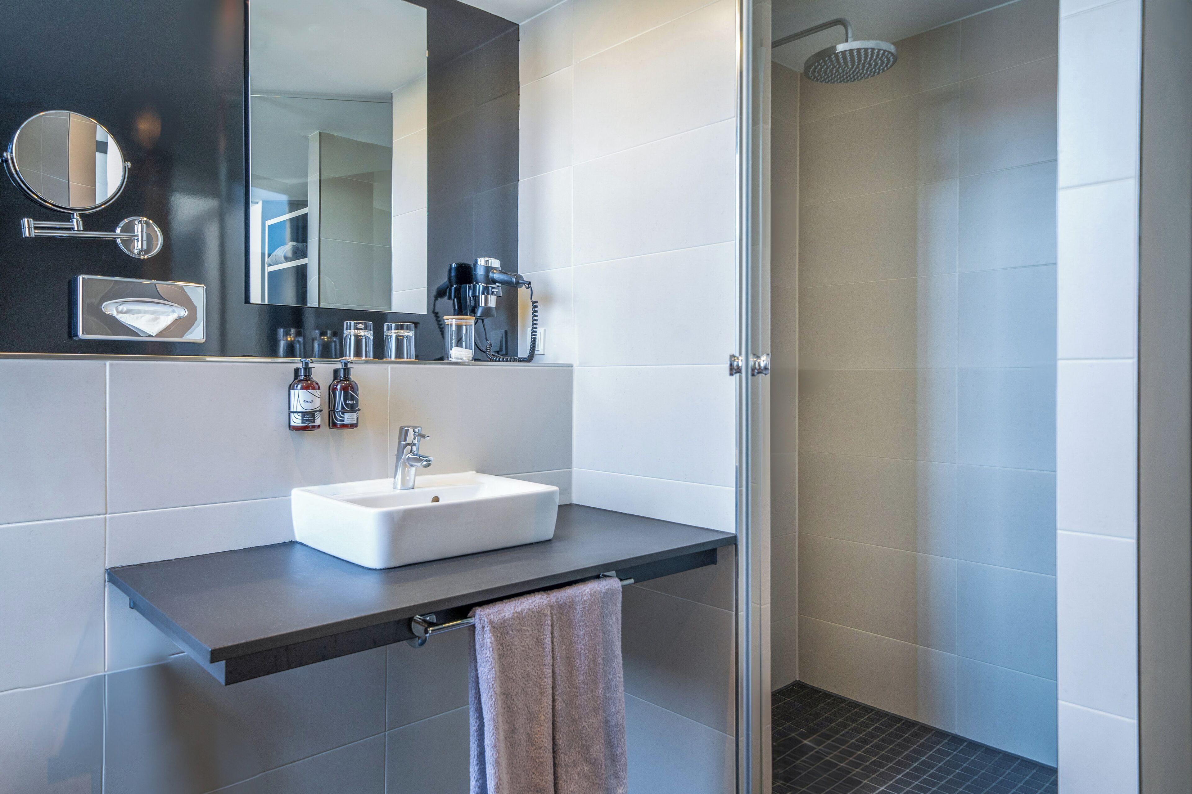A modern bathroom with a white sink, a mirror, and a shower.