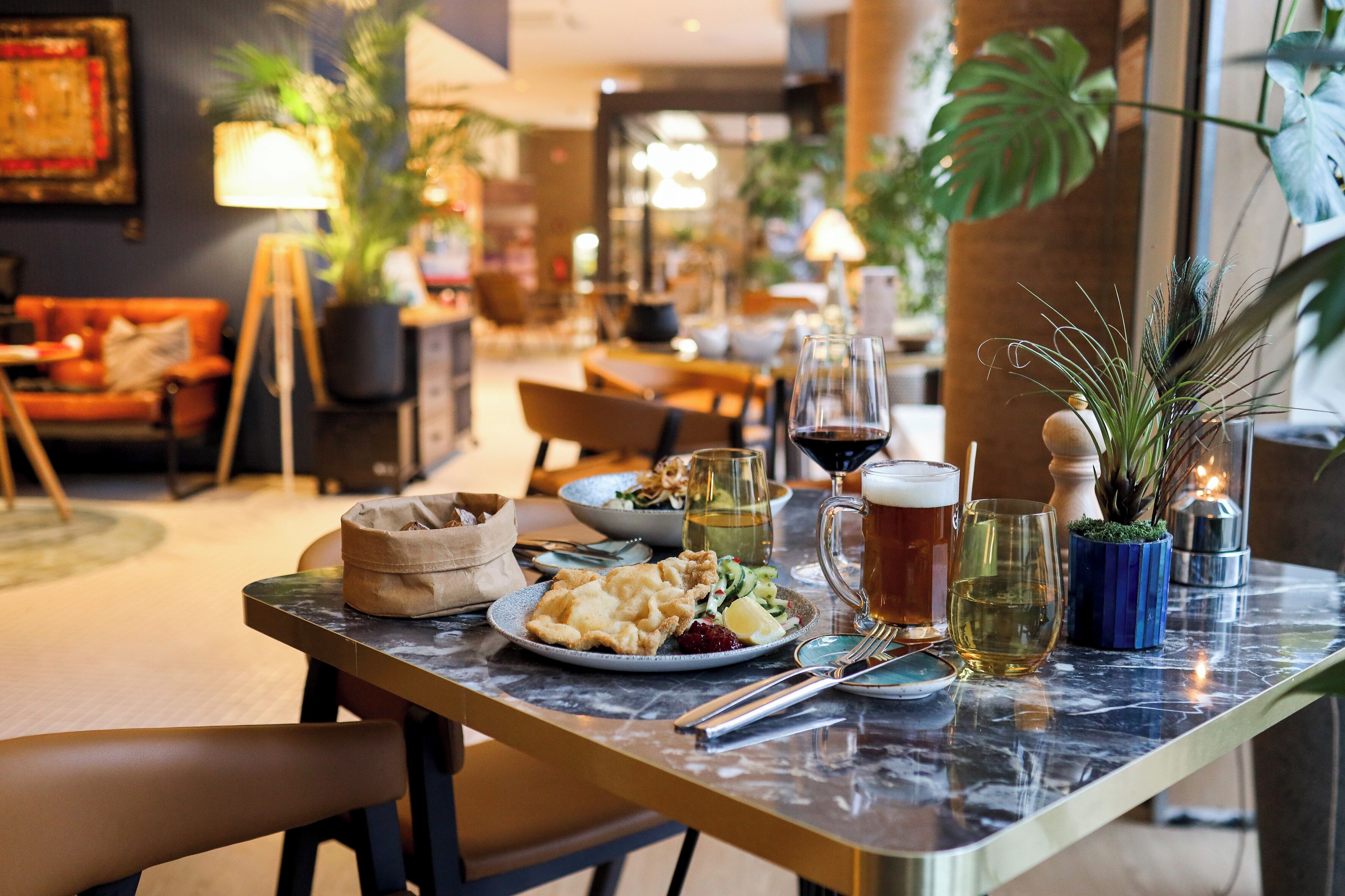A dining table with a variety of dishes, drinks, and a potted plant.
