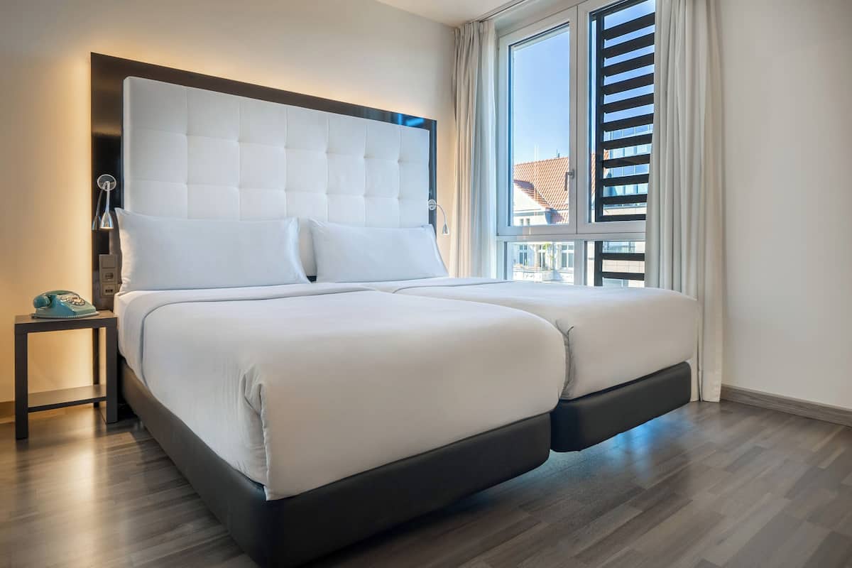 Un dormitorio moderno con una cama grande, una mesita de noche y una ventana con persianas.