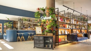 Eine moderne Bar mit einer blauen Theke, Hockstühlen und einer dekorativen Pflanzengruppe.