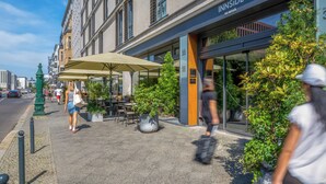 Ein Gebäude mit einer Schaufensterfassade, auf der "INNSIDE BY MELIA" steht, und Außenplätzen mit Sonnenschirmen.