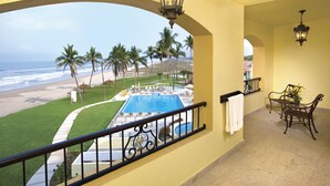 A balcony with a pool, palm trees, and a view of the beach. - Las Villas Hotel & Golf by Estrella del Mar (Mazatlán)