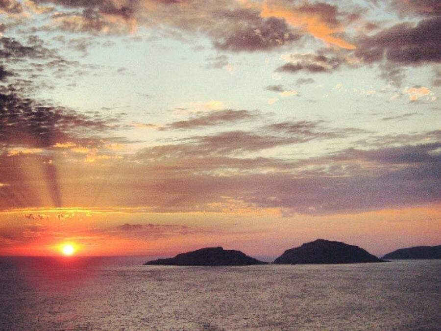 A sunset over water with distant landforms.