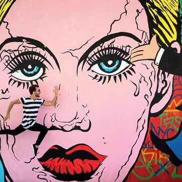 A mural with a large face, a person in a striped shirt, and a character in a top hat.