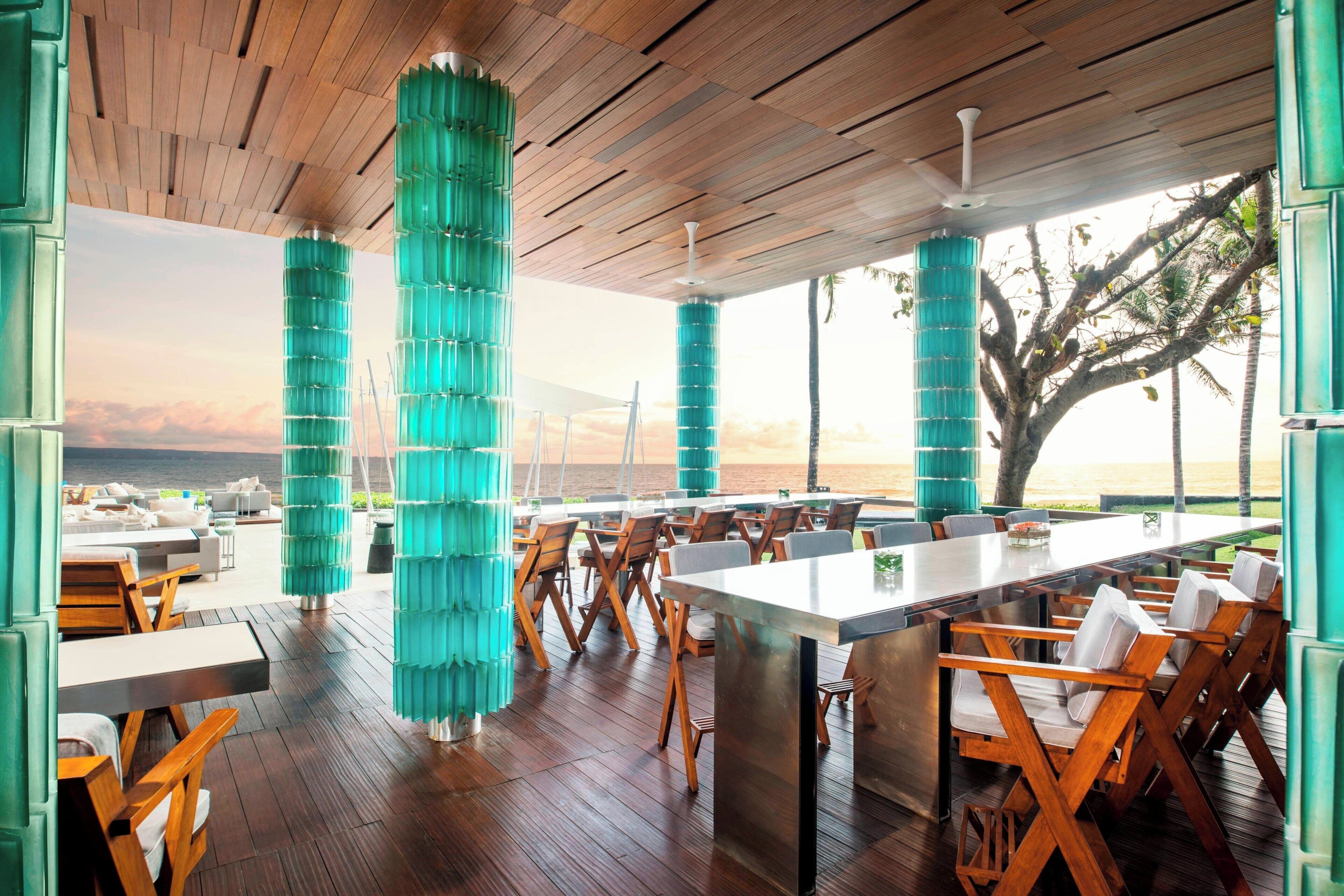 Un comedor amplio con una mesa larga y sillas, piso de madera y vistas al océano.