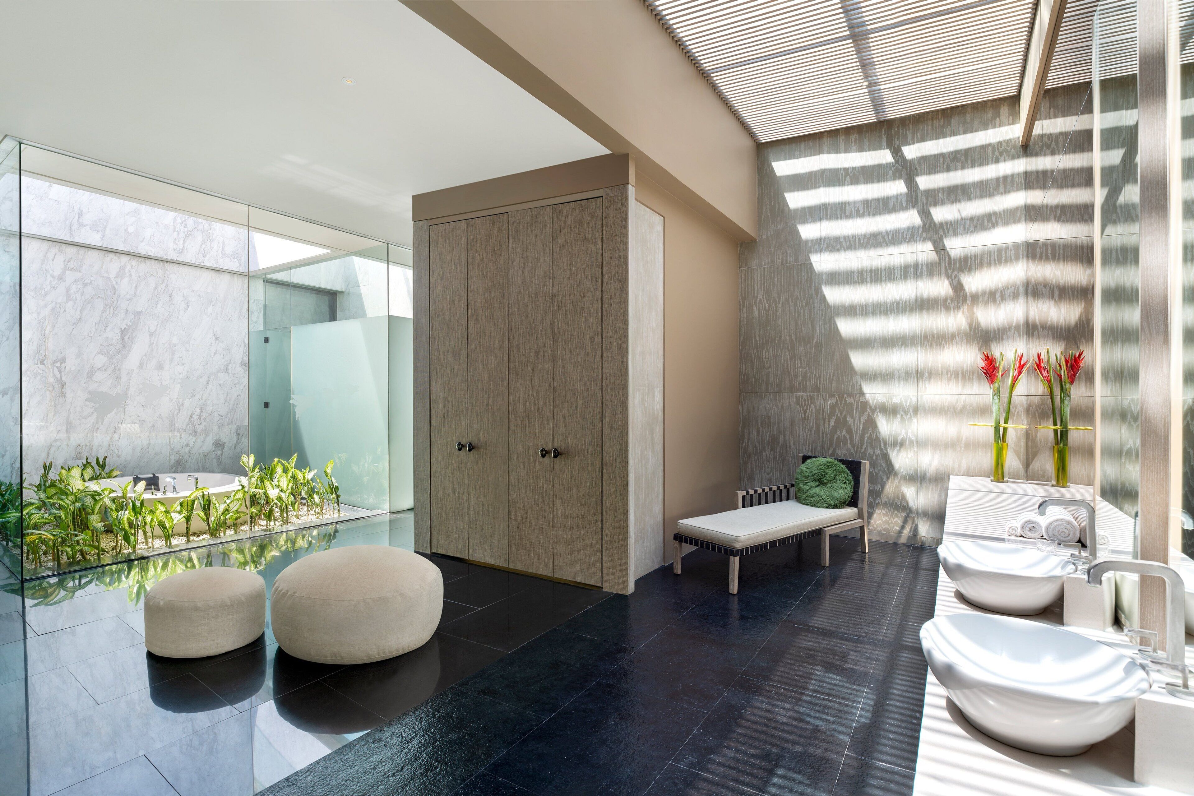 A modern bathroom with a glass-enclosed shower, a bench, and a vanity with a sink and towel rack.