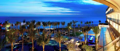 Un hotel con area piscina circondata da palme, vista sull'oceano e un design architettonico moderno.