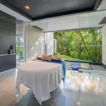 A modern bedroom with a large bed, a bedside table, and a view of a lush garden.
