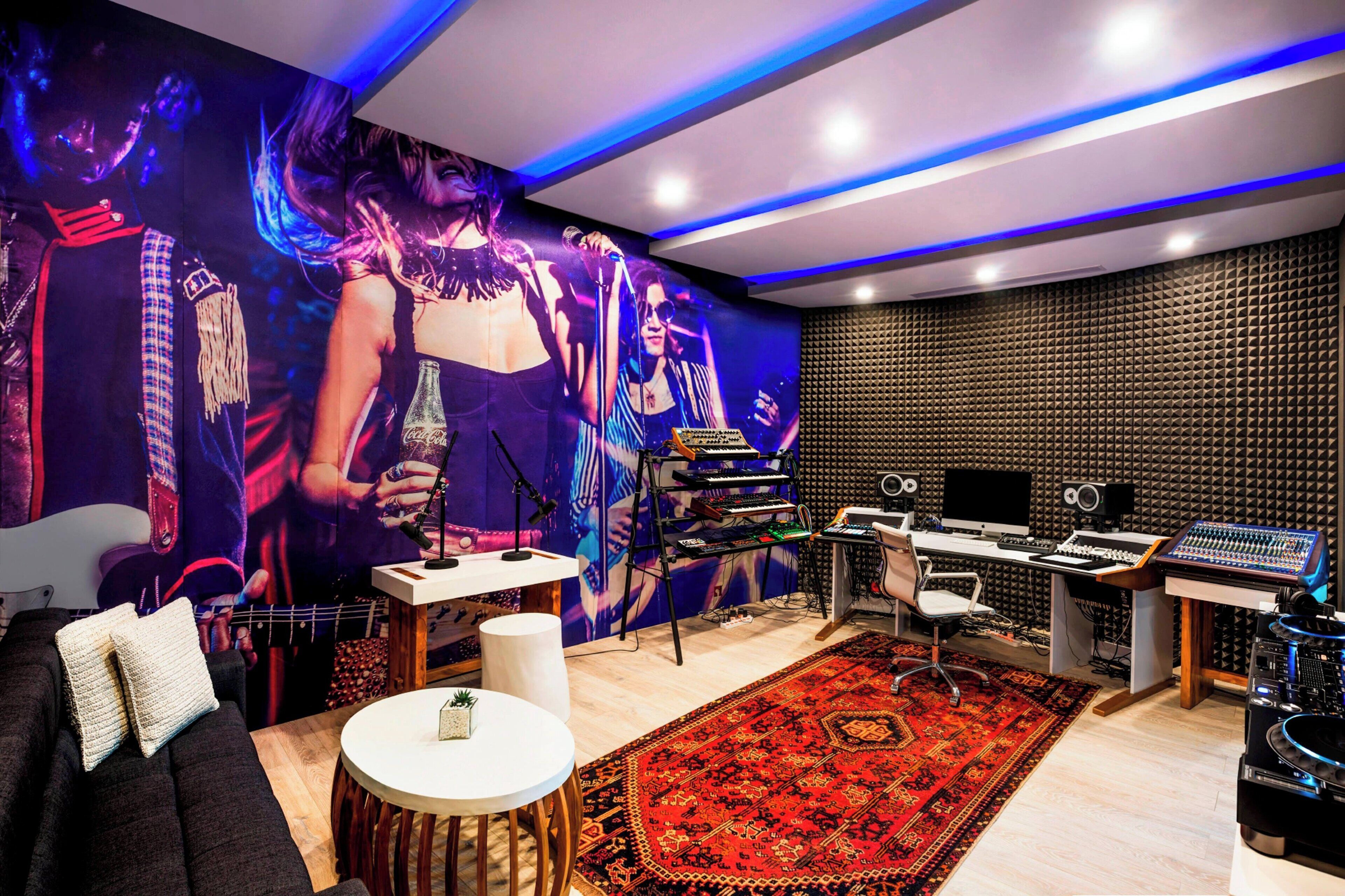 Ein modernes Aufnahmestudio mit einer großen Wandmalerei, Akustikpaneelen und professioneller Audioausrüstung.
