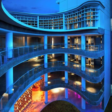 A multi-level building with a curved design, featuring balconies and a central open space.
