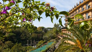 Un hotel con un largo pasillo, asientos exteriores y abundante vegetación.